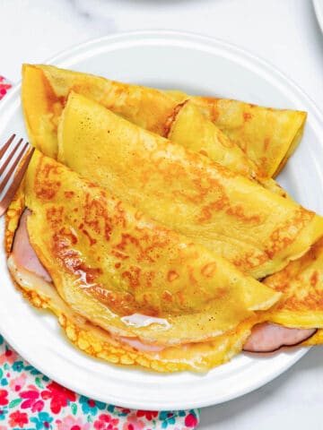 View of multiple ham and cheese crepes made with pancake mix on a white plate