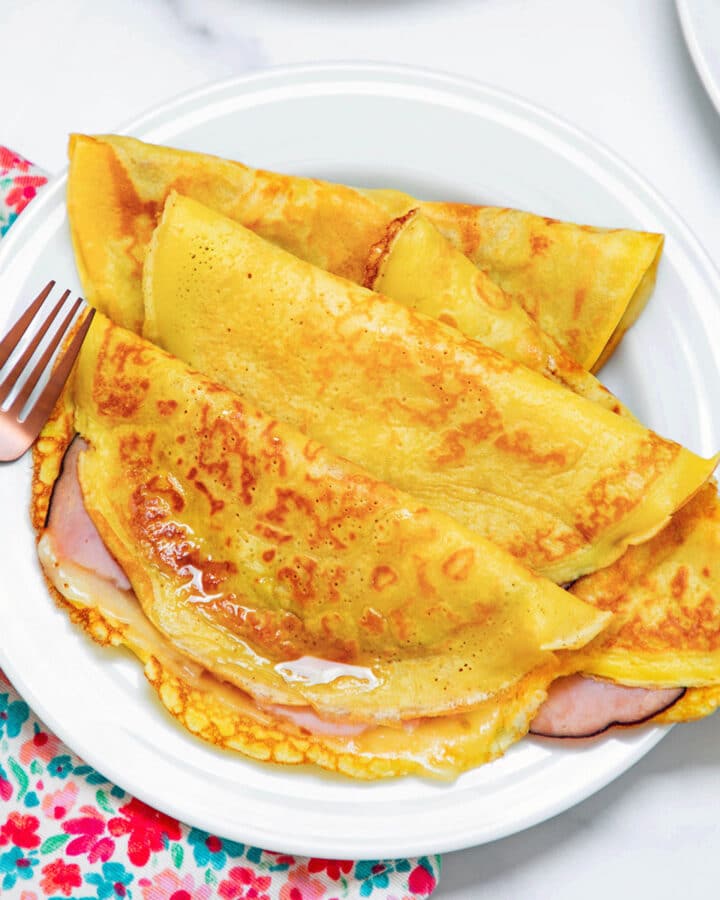 View of multiple ham and cheese crepes made with pancake mix on a white plate