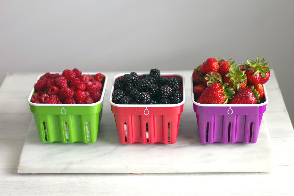 Raspberries, blackberries, and strawberries in Crisp brand berry baskets all in a row