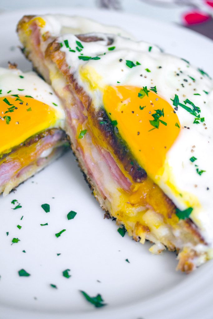 Overhead close-up view of a croque madame with egg on top cut in half