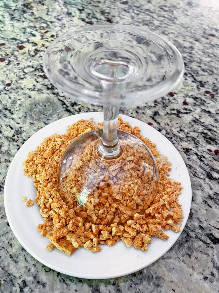 Upside-down cocktail glass on a plate of crushed Cinnamon Toast Crunch cereal