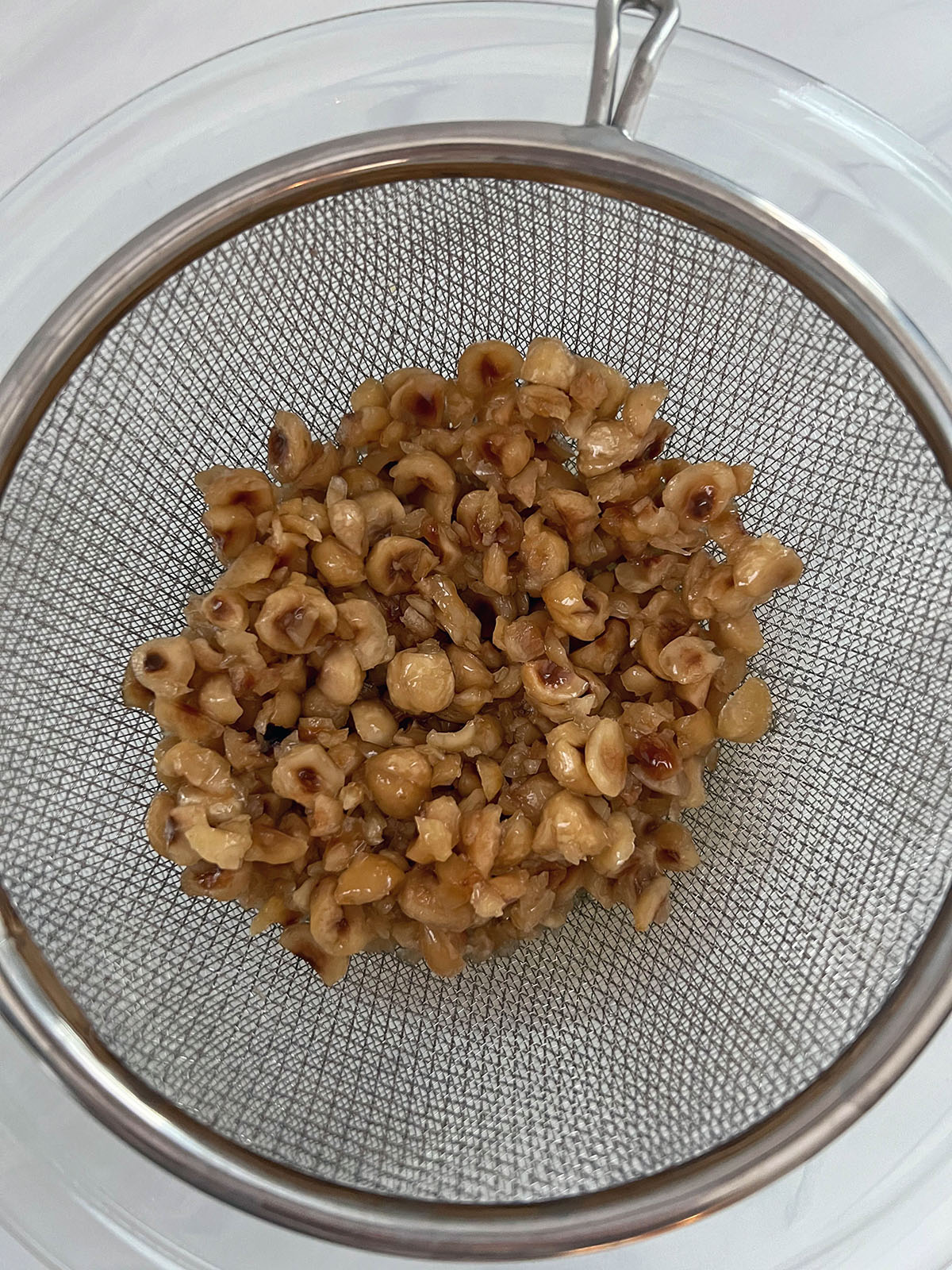 Hazelnuts being strained out of syrup.