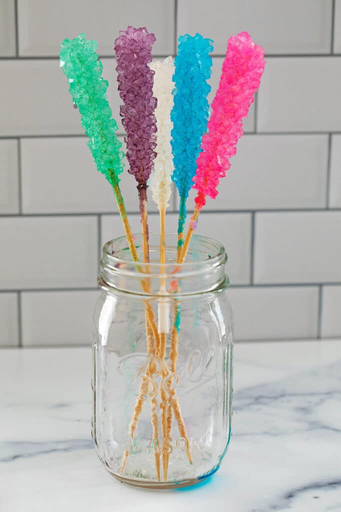 Mason jar filled with 5 different colors of rock candy on sticks