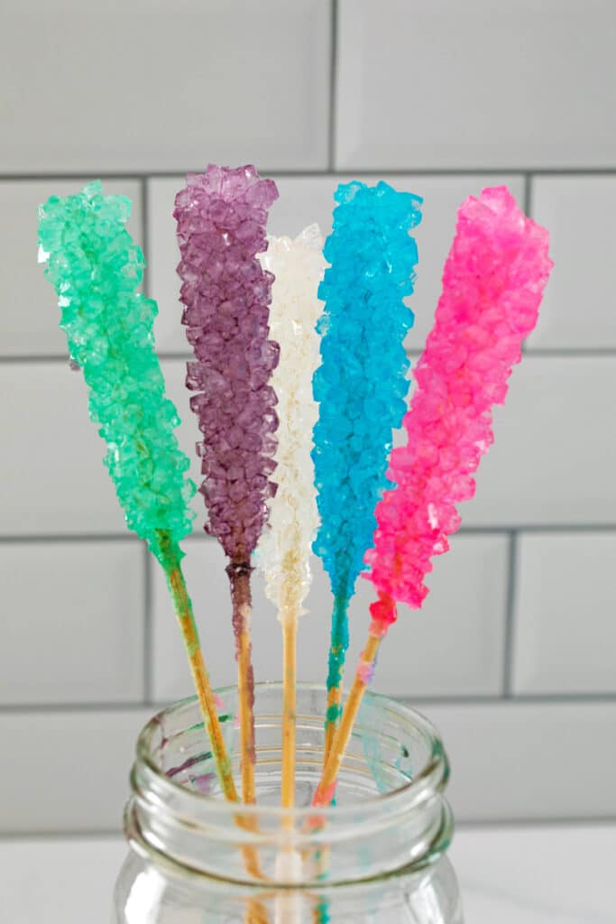 Mason jar filled with 5 different colors of rock candy on sticks