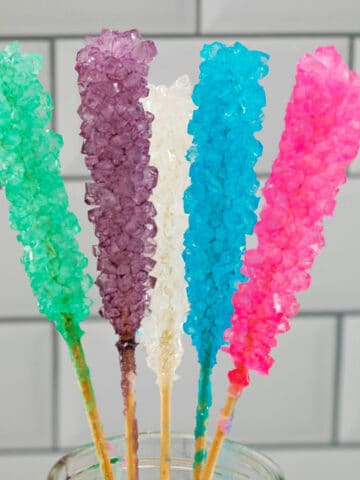 Mason jar filled with 5 different colors of rock candy on sticks