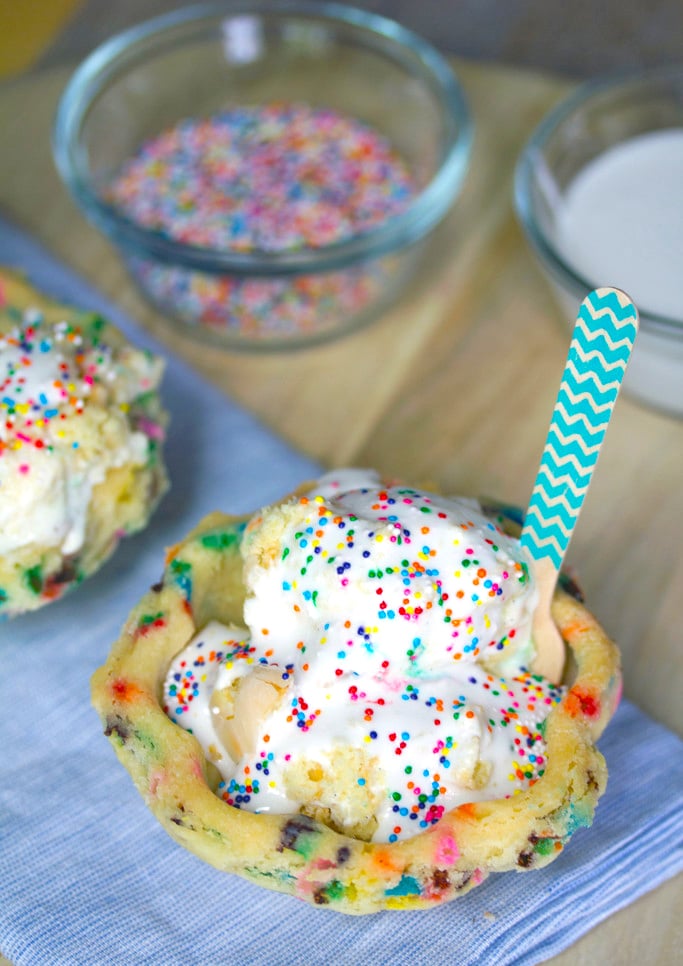 Overhead view of edible cookie bowl filled with ice cream and topped with marshmallow sauce and sprinkles with sprinkles in the background