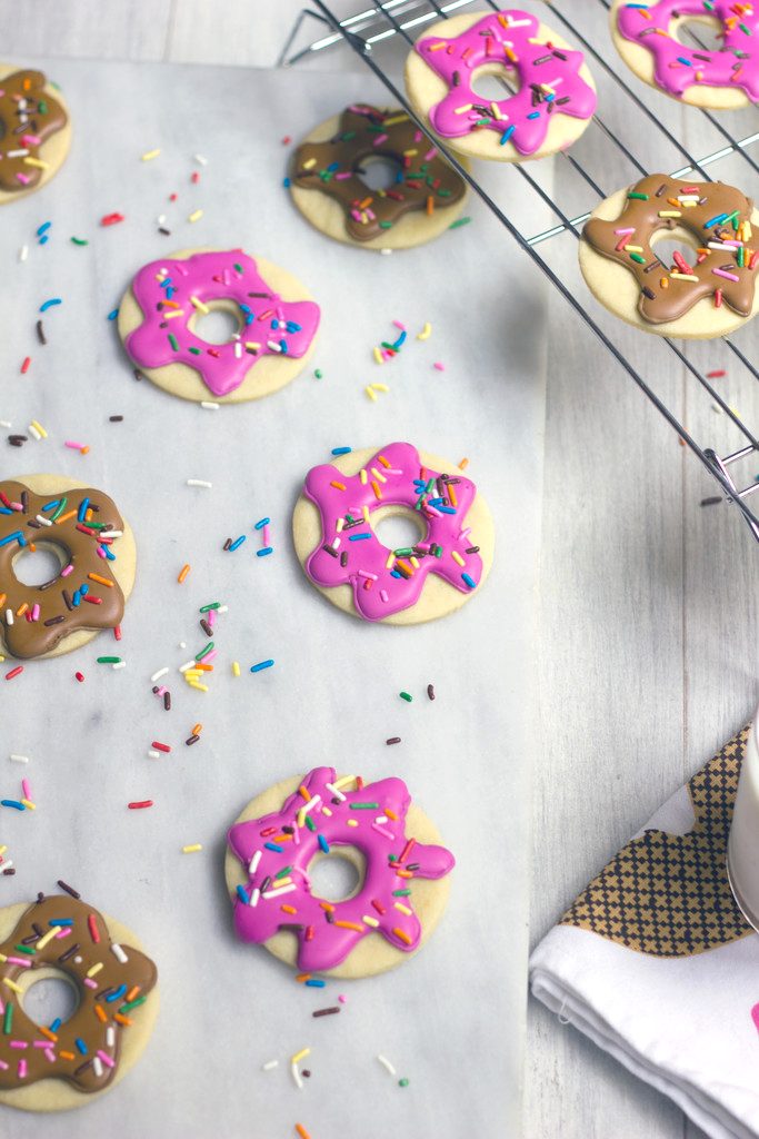 Bird's eye view of doughnut sugar cookies on a marble tray with baking rack with more donut cookies on it