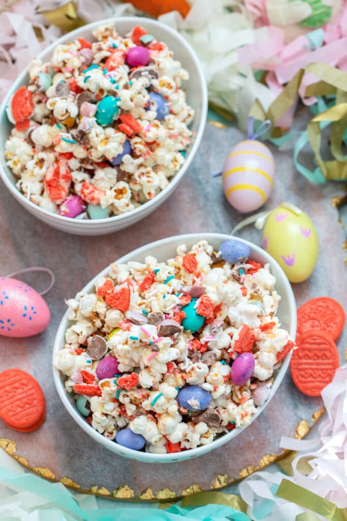 Bird's eye view of two bowls of Easter candy popcorn surrounded by Easer eggs and Oreo cookies