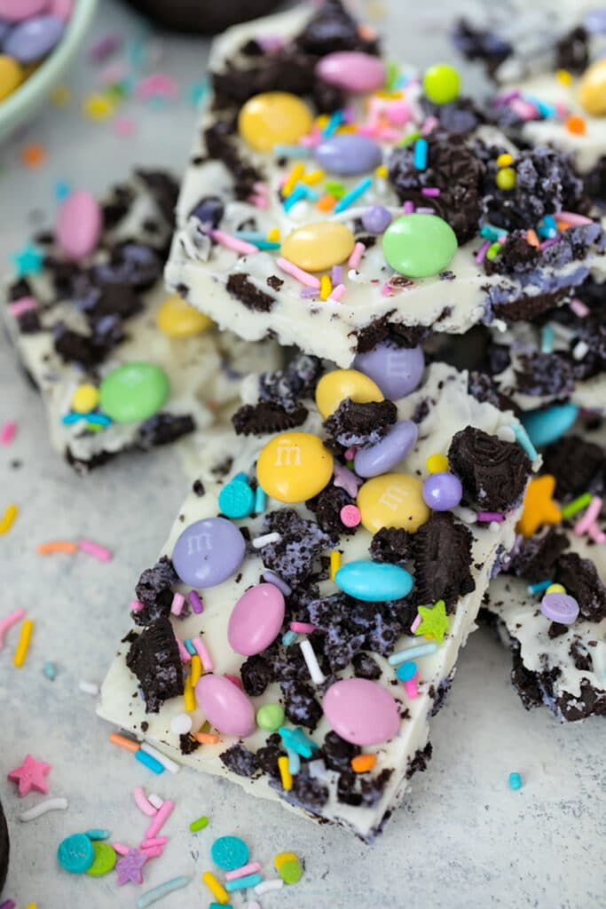 Overhead view of pieces of white chocolate Easter Oreo bark with spring M&Ms, Peeps Oreo cookies, and pastel sprinkles