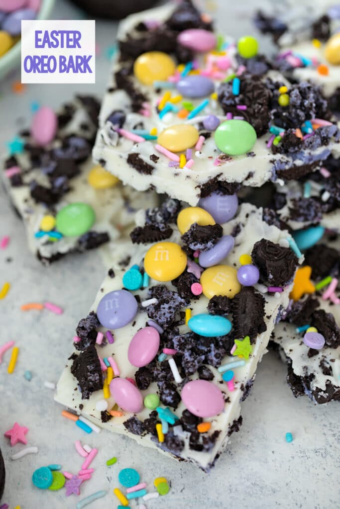 Overhead view of pieces of white chocolate Easter Oreo bark with spring M&Ms, Peeps Oreo cookies, and pastel sprinkles with recipe title at top.