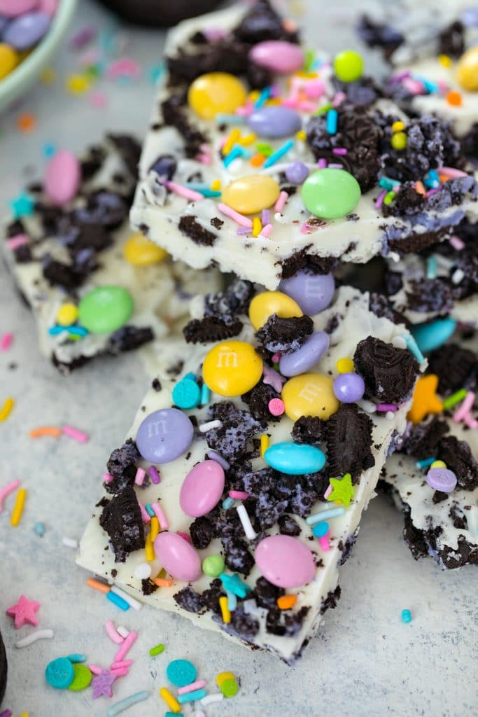 Overhead view of pieces of white chocolate Easter Oreo bark with spring M&Ms, Peeps Oreo cookies, and pastel sprinkles