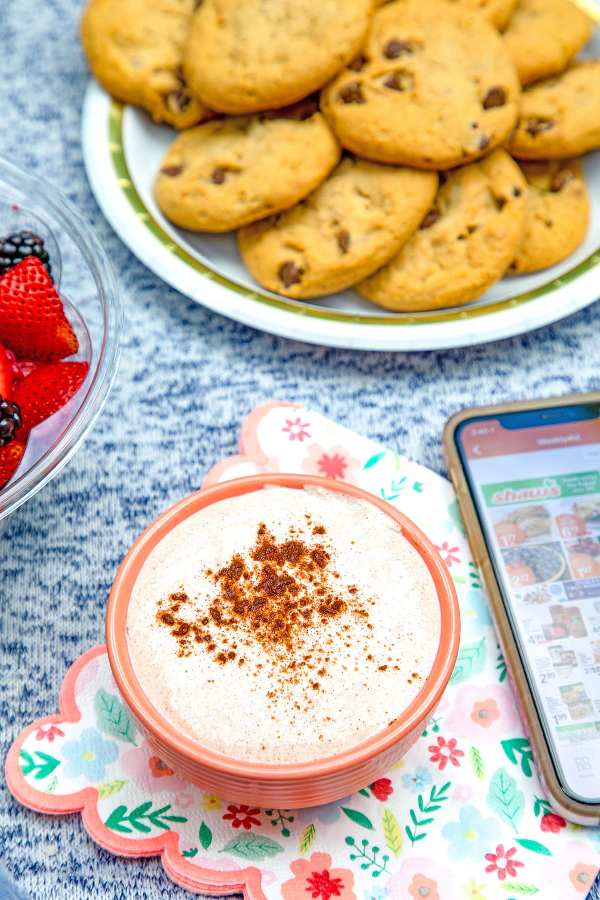 Small bowl of cinnamon dessert dip with plate of cookies in background and phone showing Shaw's app.