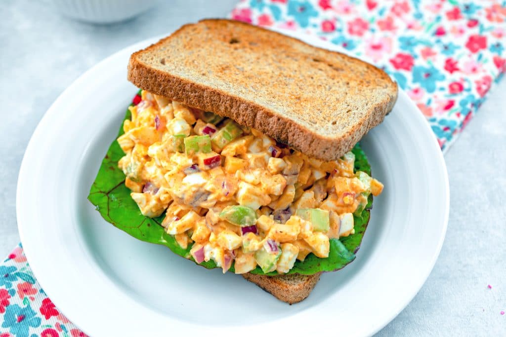 Landscape view of egg salad sandwich with onion, apple, and celery and Swiss chard