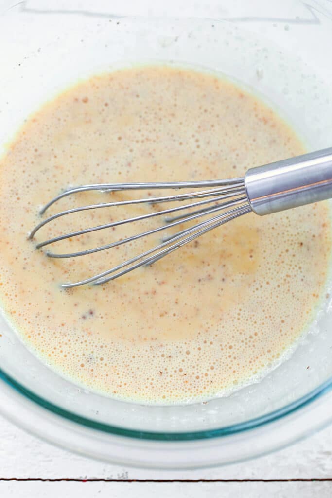Eggnog, maple syrup, and vanilla being whisked together