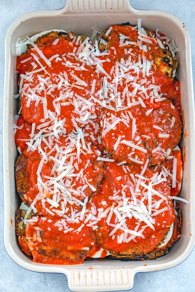 Overhead view of eggplant parmesan ingredients layered in casserole dish and ready to go in the oven