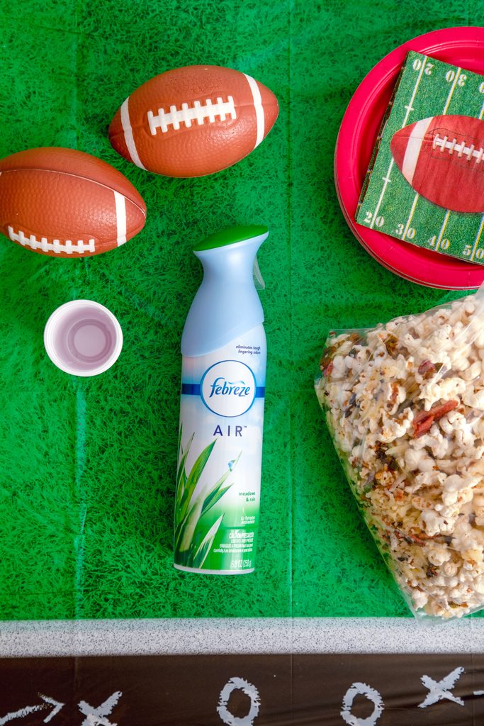 Bird's eye view of Febreze AIR on football field tablecloth with popcorn in a bag, mini footballs, cups, football napkins, and plates on a football field tablecloth