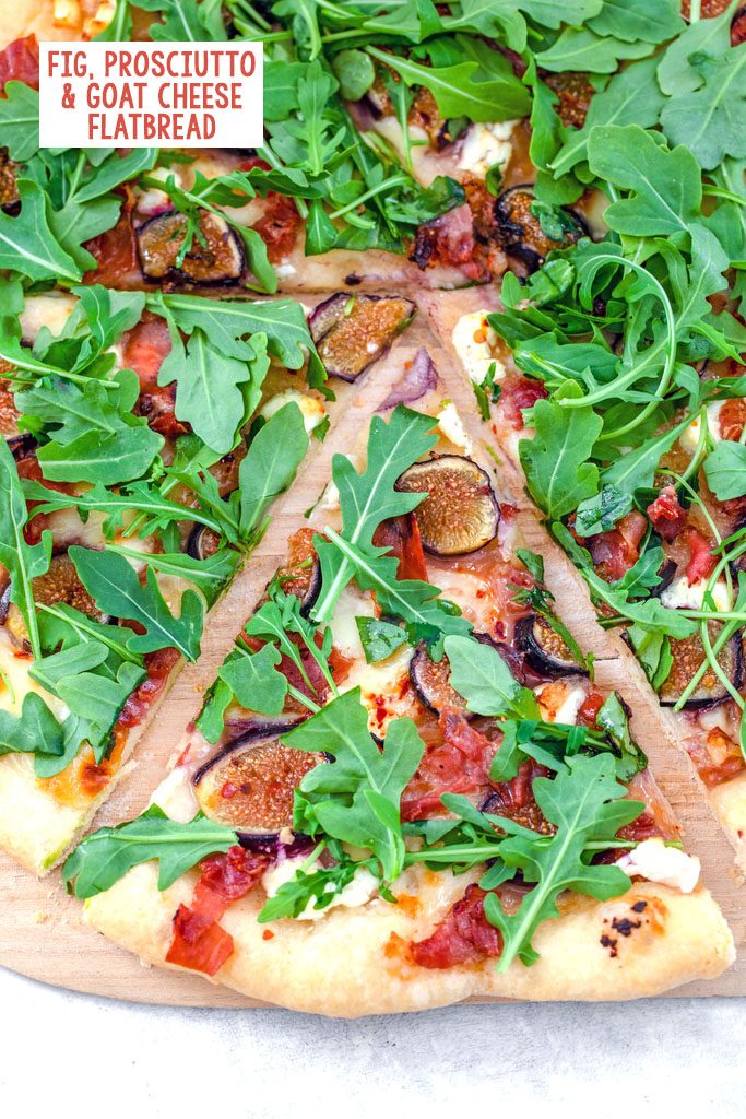 Overhead view of a slice of fig, prosciutto, and goat cheese flatbread topped with arugula and pulled out from the rest of the pizza with recipe title at top