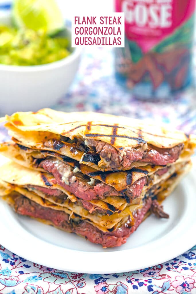 Head-on view of flank steak quesadillas with gorgonzola stacked on each other with bowl of mashed avocado and beer can in the background and recipe title at top