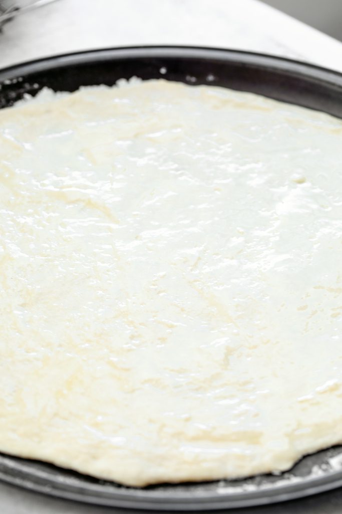 Overhead view of flatbread dough rolled out on pan