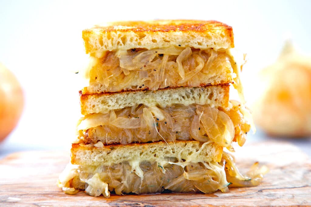 Landscape head-on view of halves of a french onion grilled cheese sandwich stacked on each other