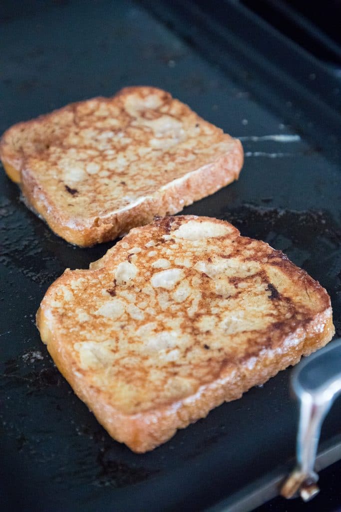 Challah bread french toast frying on a griddle