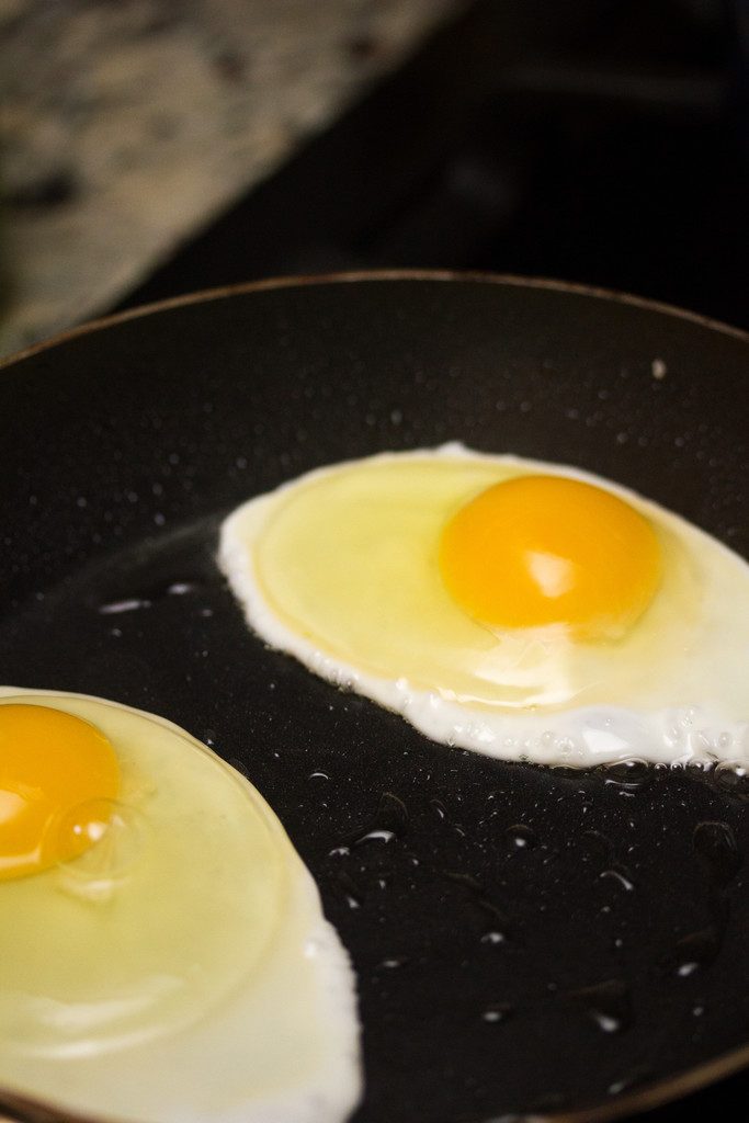 Overhead view of eggs frying in a skillet