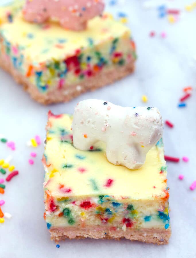 Frosted Animal Cracker Cheesecake Bars -- These Frosted Animal Cracker Cheesecake Bars consist of funfetti cheesecake with a circus animal cookie crust. Basically, your childhood in cheesecake form! | wearenotmartha.com
