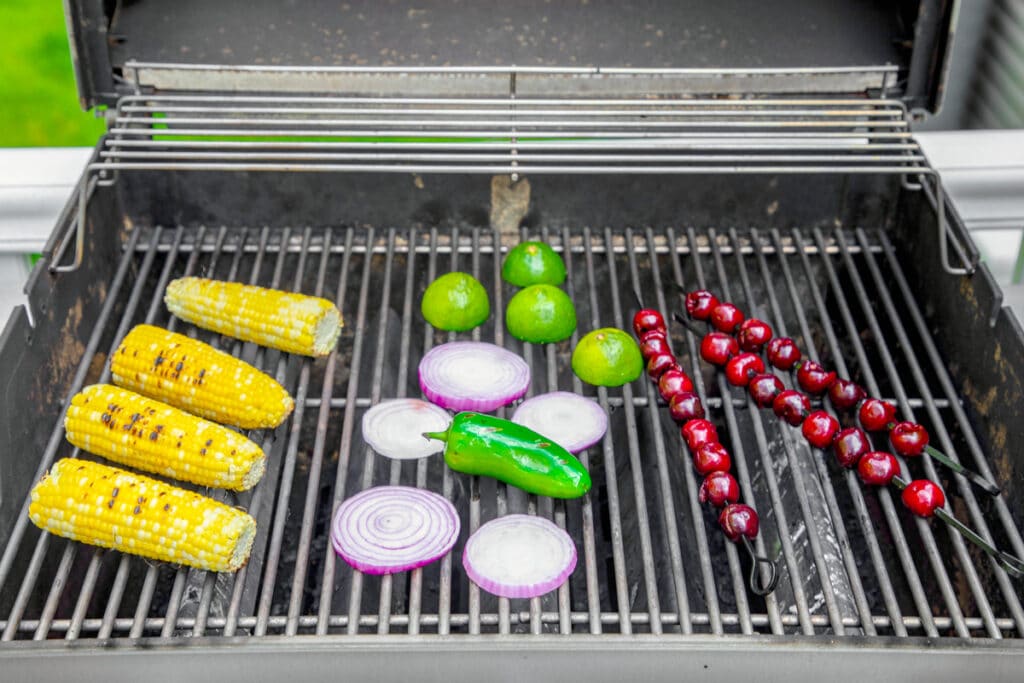 Cherries, corn, red onion, jalapeño, and limes on grill