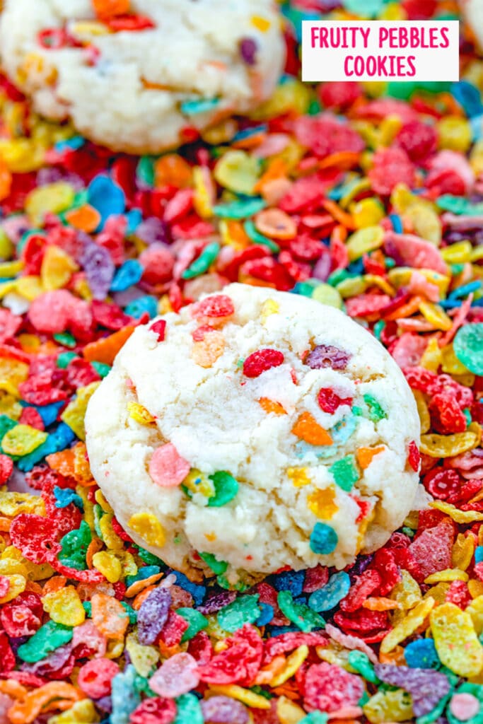 Overhead view of a Fruity Pebbles cookie sitting on a bed of Fruity Pebbles cereal with the recipe title at the top