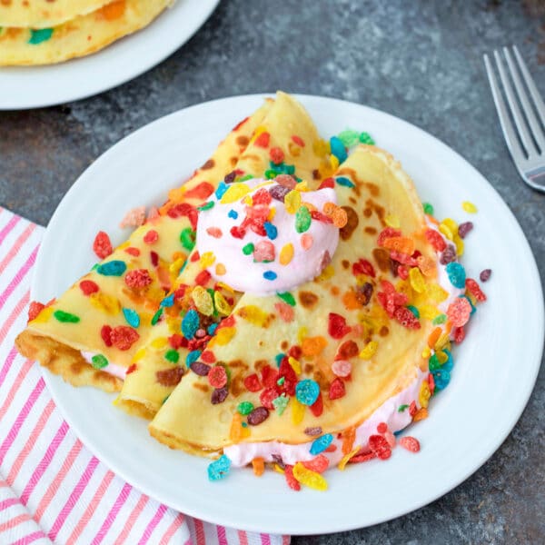 Fruity Pebbles Crepes -- Wake up to a fun and cheery breakfast of Fruity Pebbles Crepes with strawberry whipped cream. These crepes are easy to make and consist of a simple batter that can be prepared ahead of time to make morning breakfast a breeze | wearenotmartha.com #crepes #creperecipes #fruitypebbles #cereal #brunch #funbreakfasts