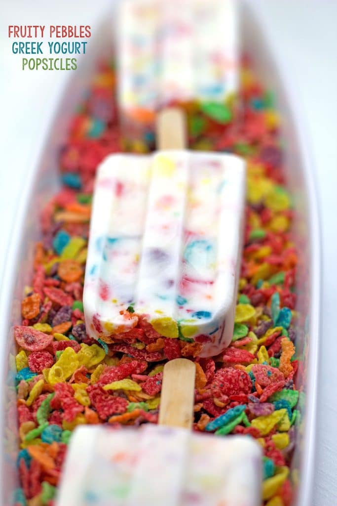 Hero image featuring row of Fruity Pebbles Greek Yogurt Popsicles facing down on a bed of Fruity Pebbles