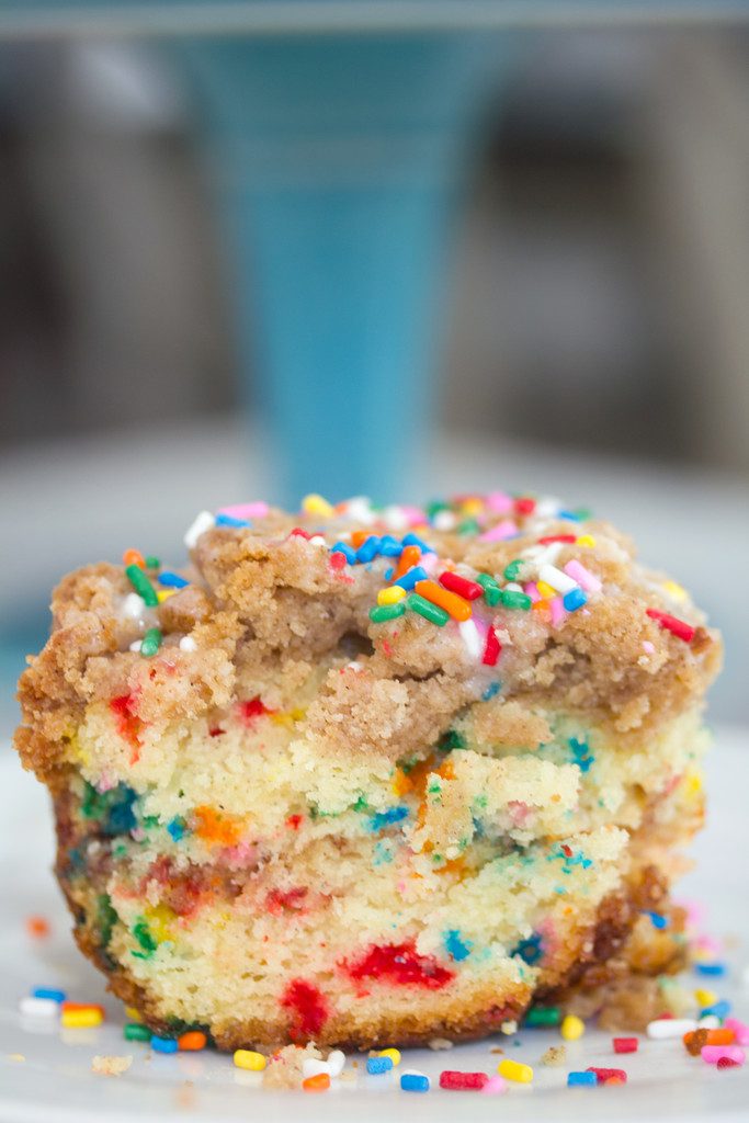 Head-on closeup view of a slice of funfetti coffee cake with crumb topping and rainbow sprinkles