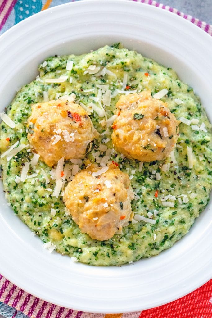 Overhead view of a white bowl filled with kale polenta and topped with three garlic habanero chicken meatballs