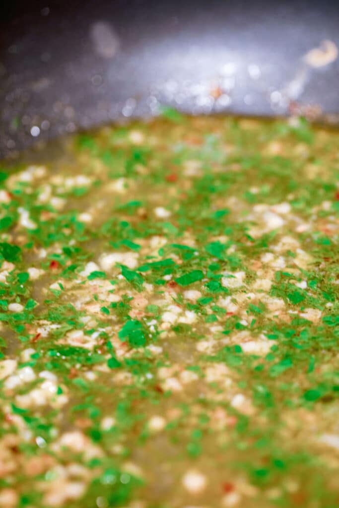 Garlic and parsley cooking in skillet.