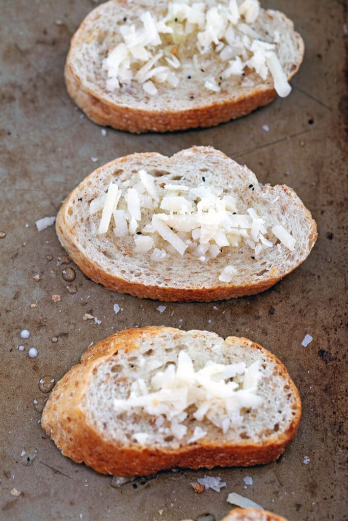 Slices of baguette topped with garlic mixture and parmesan cheese