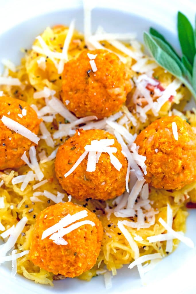 Close-up of pumpkin chicken meatballs topped with parmesan cheese over garlicky spaghetti squash with sage