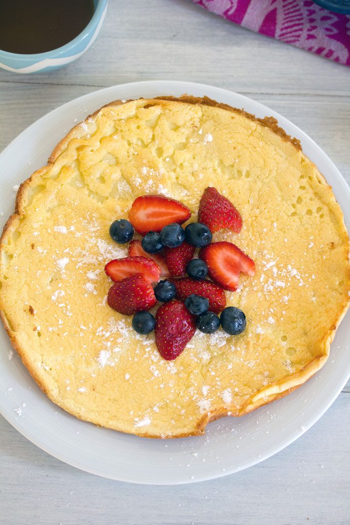 Overhead view of a large German pancake topped with berries and powdered sugar