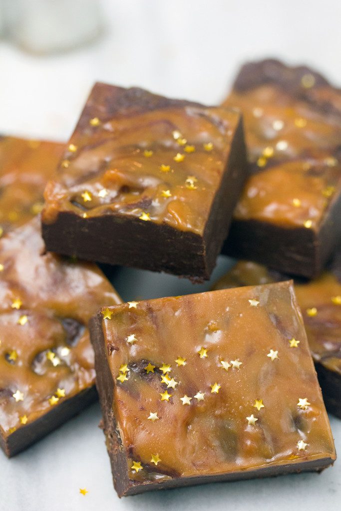 Head-on view of a pile of gingerbread fudge with chocolate and caramel with gold star sprinkles