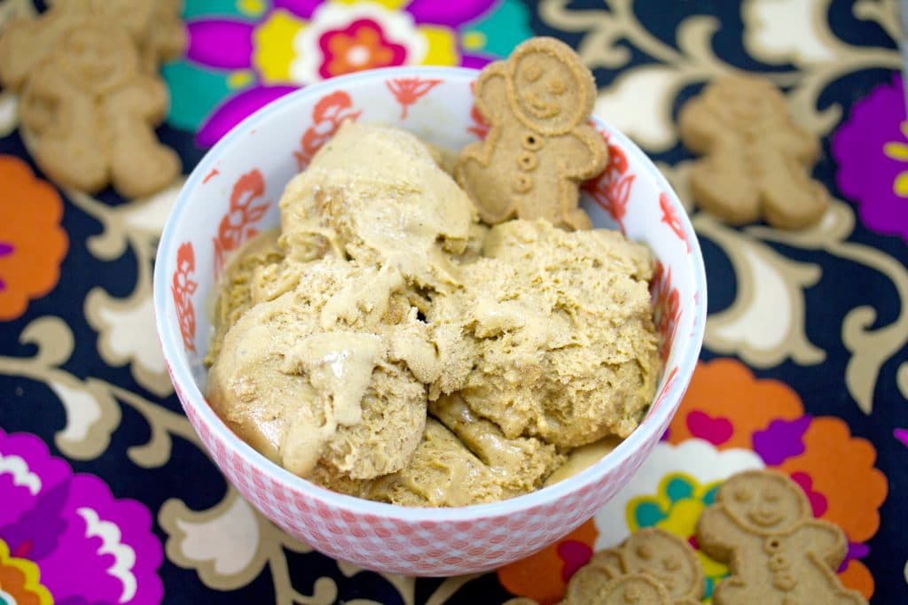 Overhead view of bowl of gingerbread ice cream with small gingerbread man garnish on floral napkin 