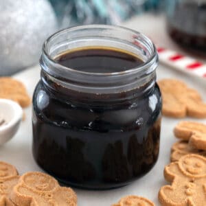 Head-on closeup view of a small jar of gingerbread syrup with gingerbread men all around
