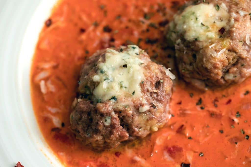 Landscape close-up view of two gorgonzola meatballs in a creamy tomato sauce