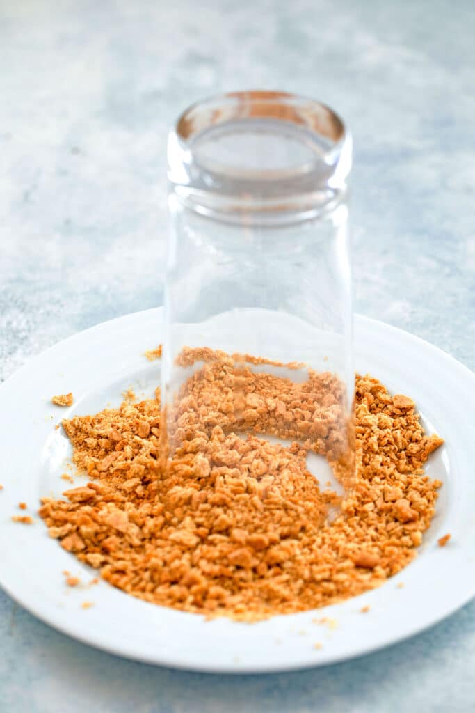 Upside down glass on a plate with crushed graham crackers