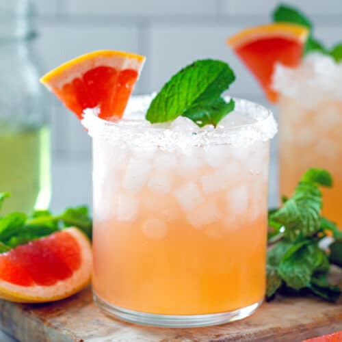 Head-on closeup view of a grapefruit mint margarita with fresh mint and grapefruit wedges all around