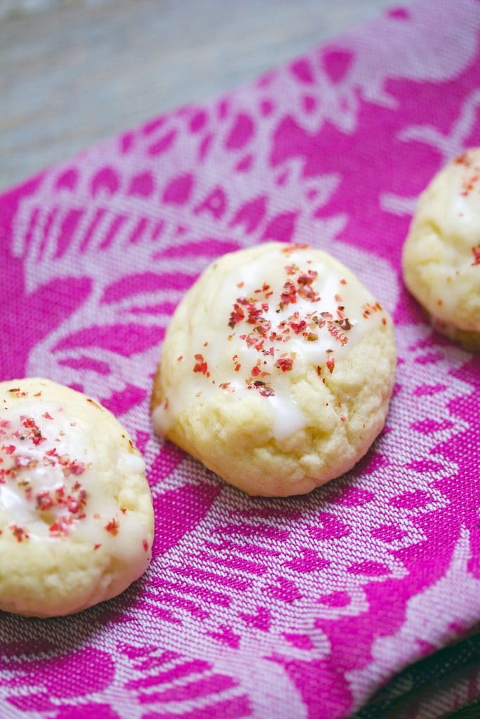 Three grapefruit pink peppercorn cookies on a pink towel