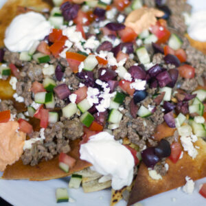 Greek Nachos with Ground Lamb -- Ever crave nachos for dinner? These Greek Nachos with Ground Lamb are piled high with veggies and hummus, making them a totally acceptable dinner. Promise. | wearenotmartha.com