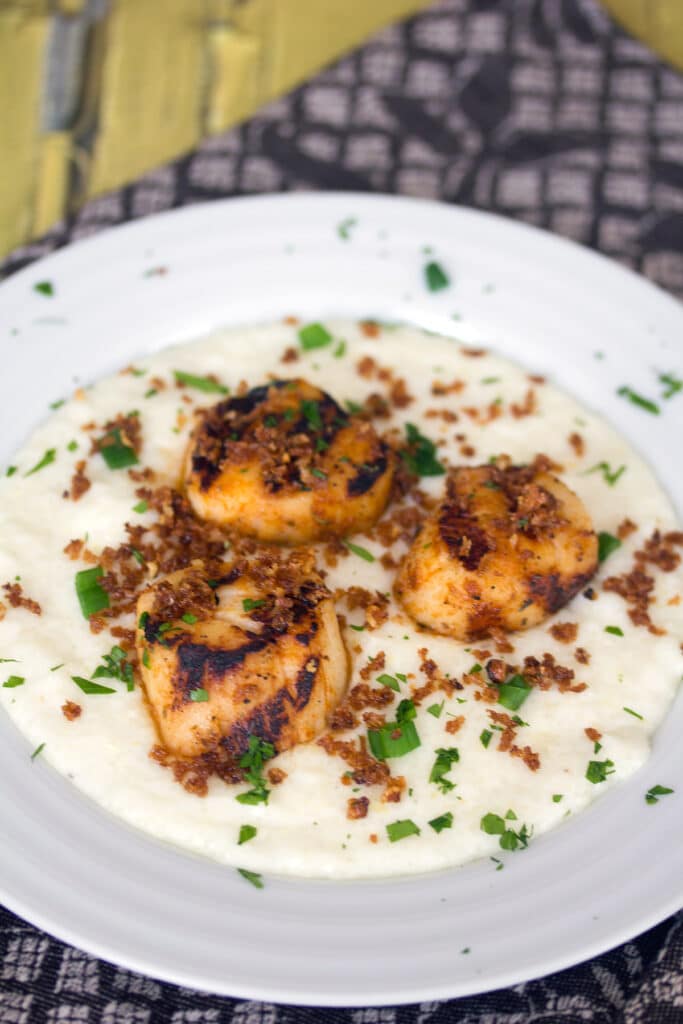 Bowl with cheesy grits topped with scallops and panko