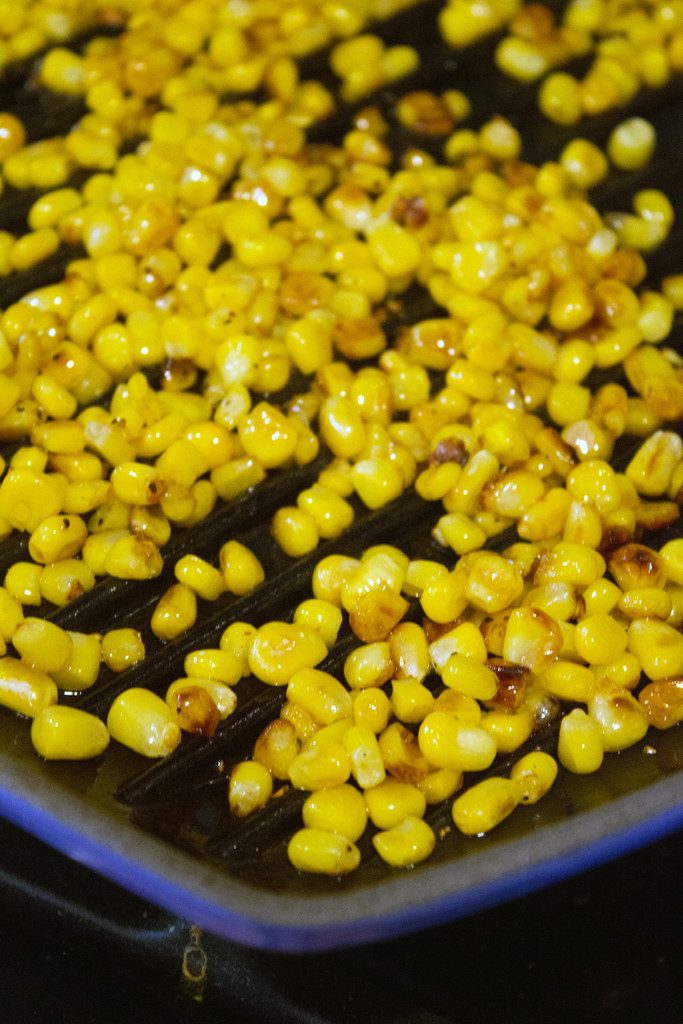 Overhead view of corn kernels cooking in grill pan