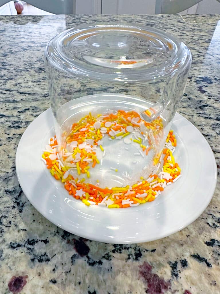 Glass upside down on plate of Halloween sprinkles.