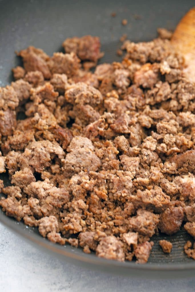 View of skillet with ground beef almost done cooking