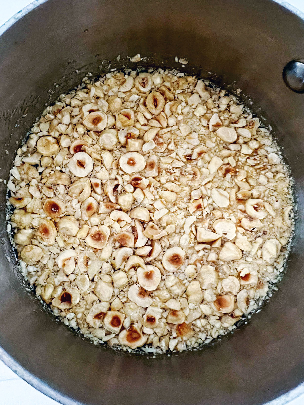 Hazelnuts in water and sugar in saucepan.